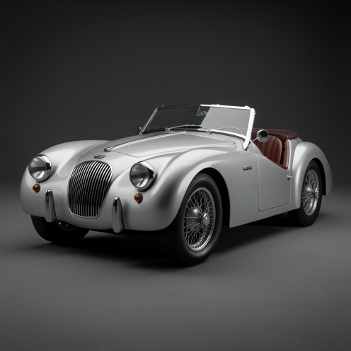 Roadster britannique ancien de 1953 à la carrosserie argentée, photographié en trois-quarts avec ses ailes arrondies, ses roues à rayons et ses chromes restaurés.